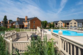 A pool surrounded by a white fence with a building in the background.